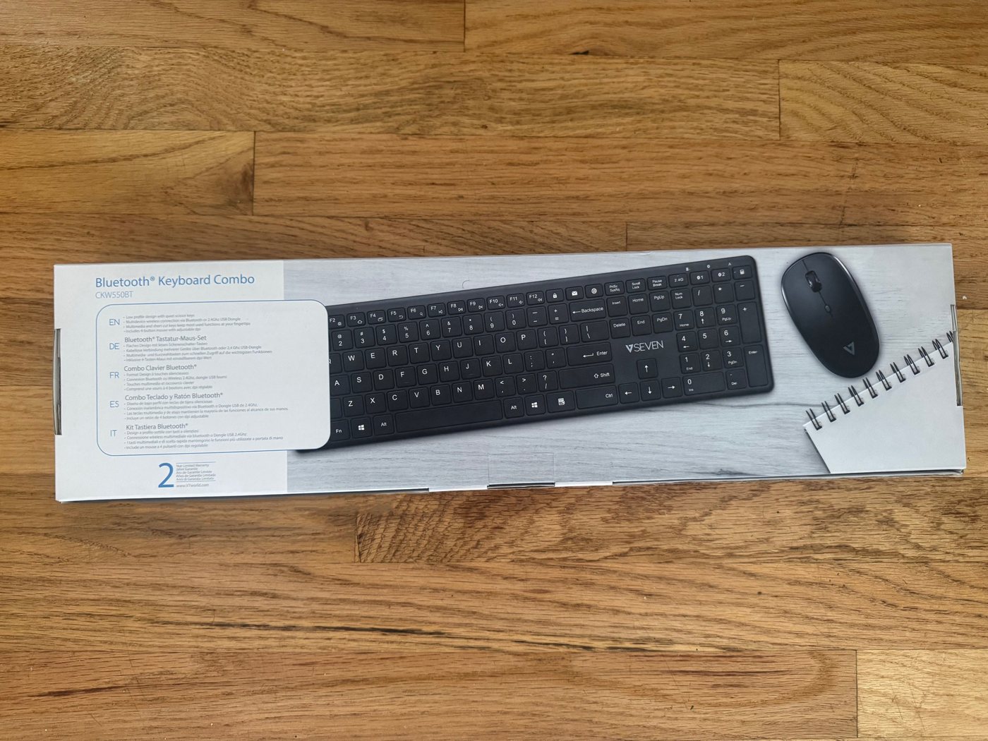 Retail box for a V7 wireless keyboard and mouse set lying on a wood floor